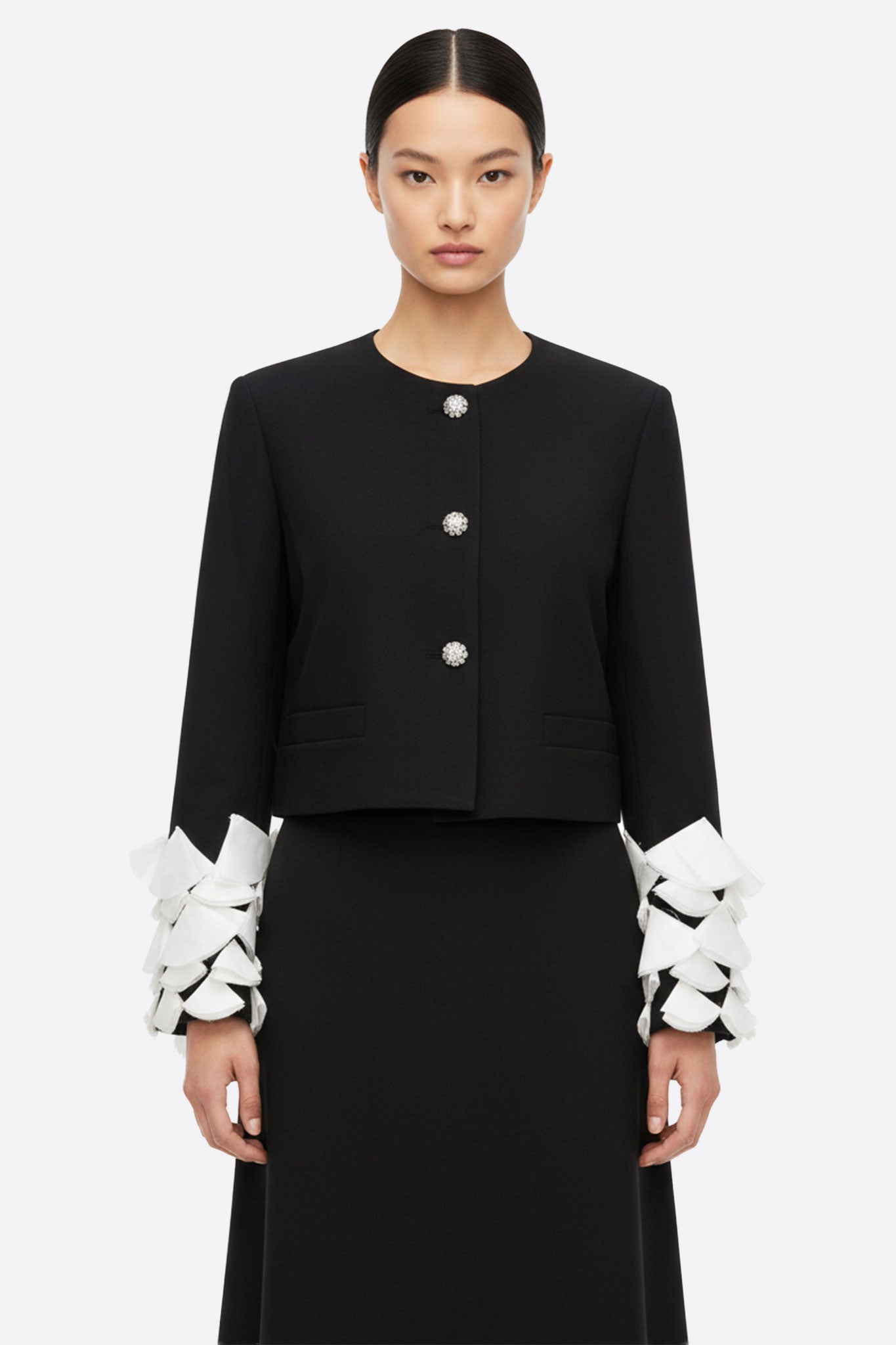 Chaqueta negra con mangas de pétalos y plumas blancas